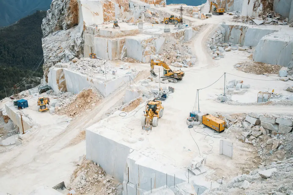 Yukarıdan görünen beyaz mermer ocağı, kesilmiş mermer duvarlar arasında çalışan iş makineleri